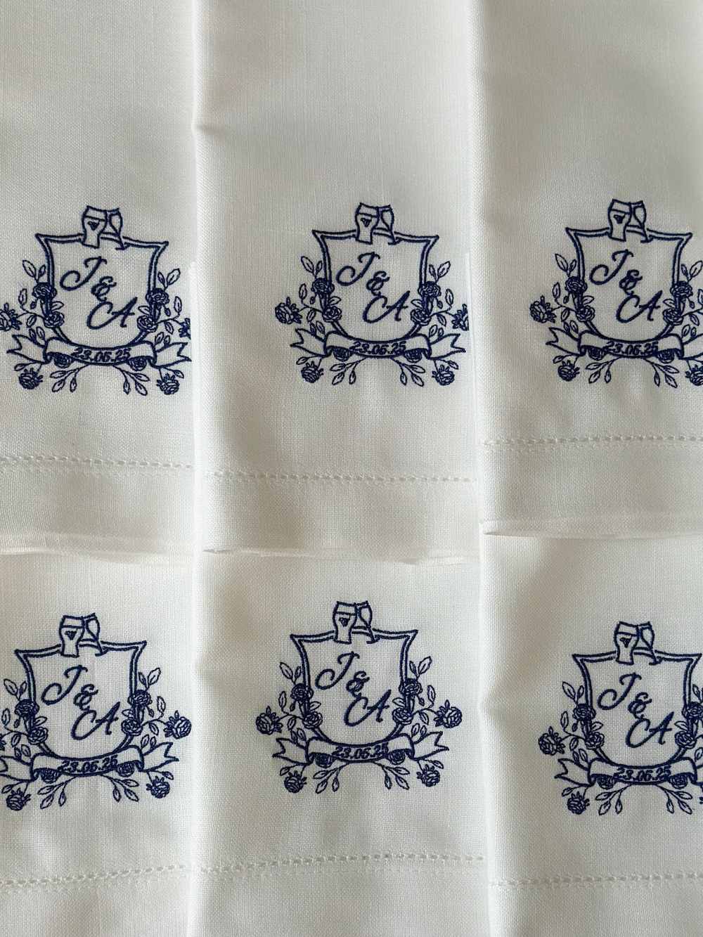 White fabric with embroidered monogram designs in a grid pattern.