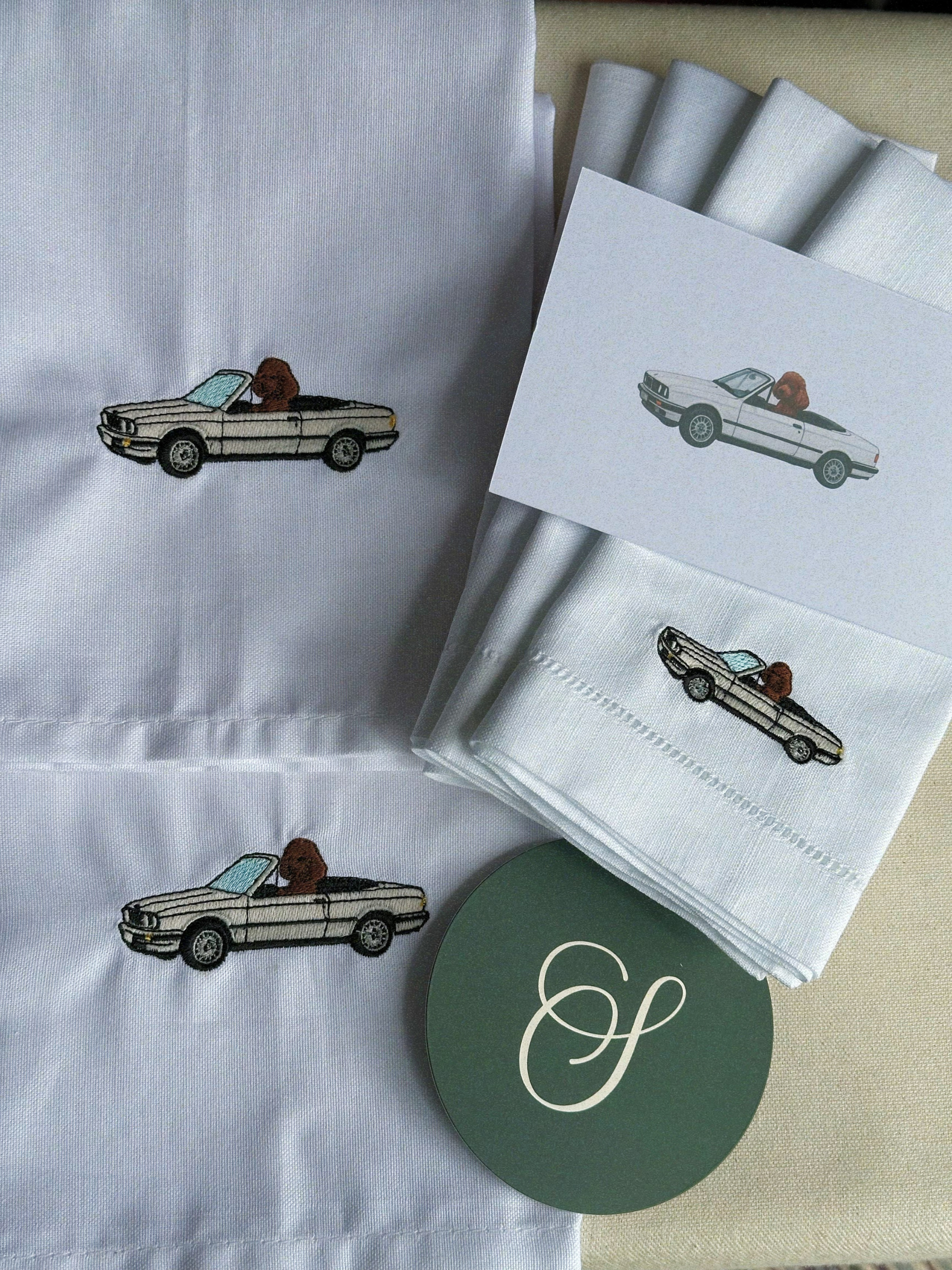 White napkins with embroidered car design on a beige surface