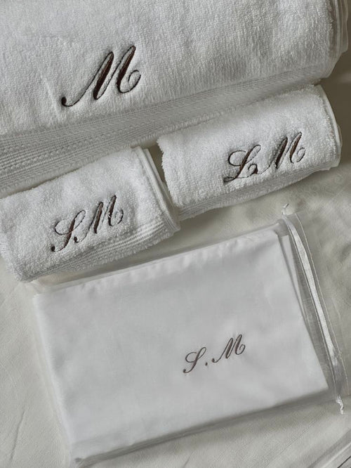 Set of white towels with embroidered initials on a light background