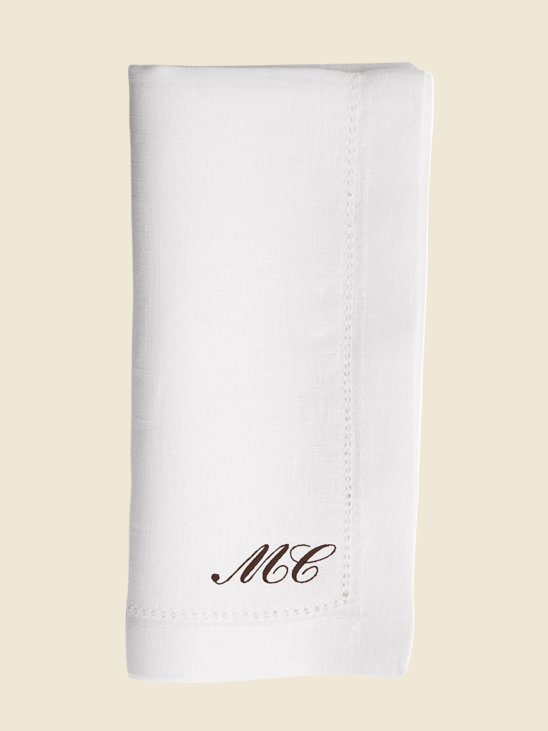 White napkin with 'MC' monogram on a white background