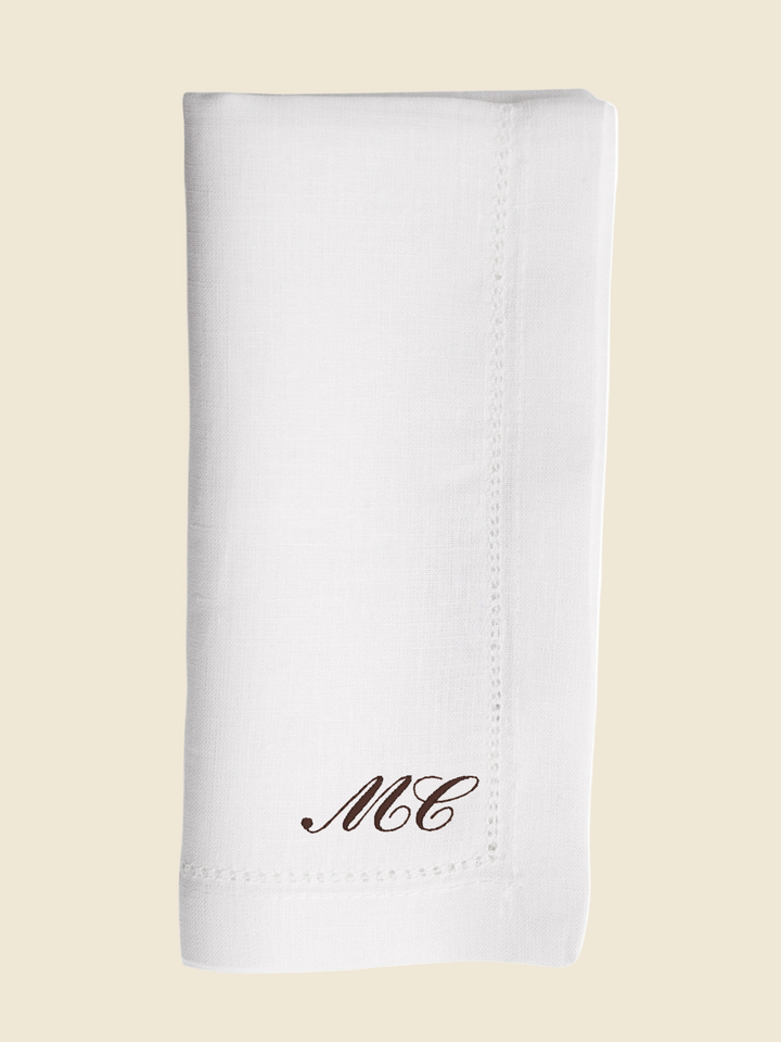 White napkin with 'MC' monogram on a white background
