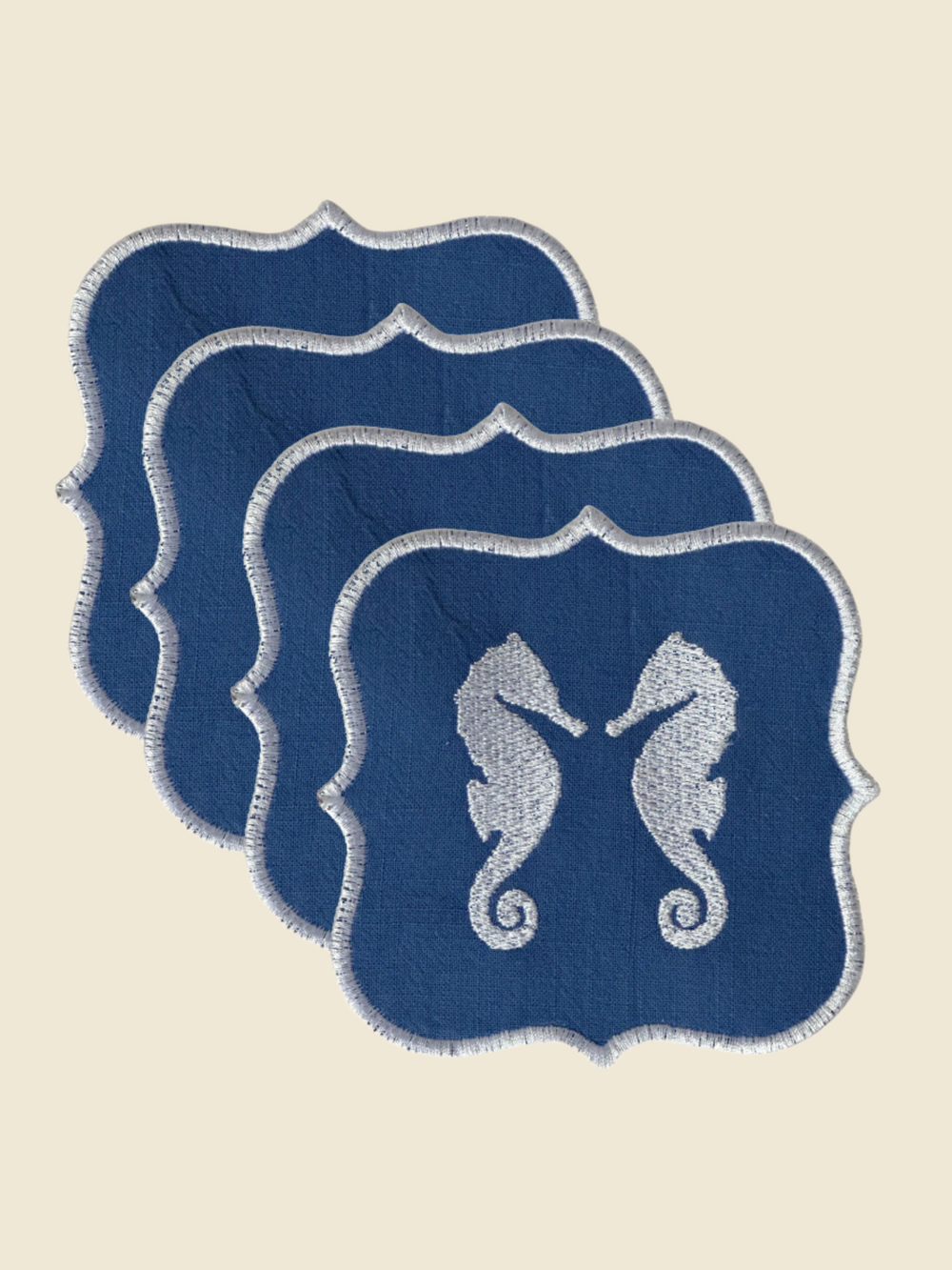 Set of four blue coasters with seahorse design on a white background