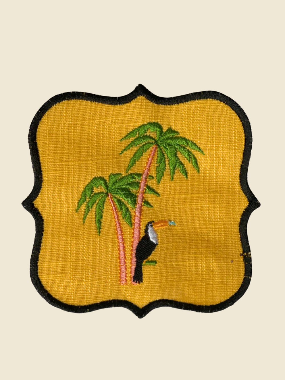 Embroidered coaster with a toucan and palm trees on a yellow background