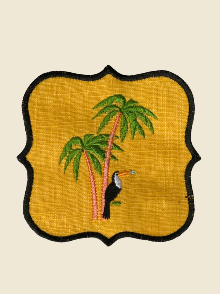 Embroidered coaster with a toucan and palm trees on a yellow background