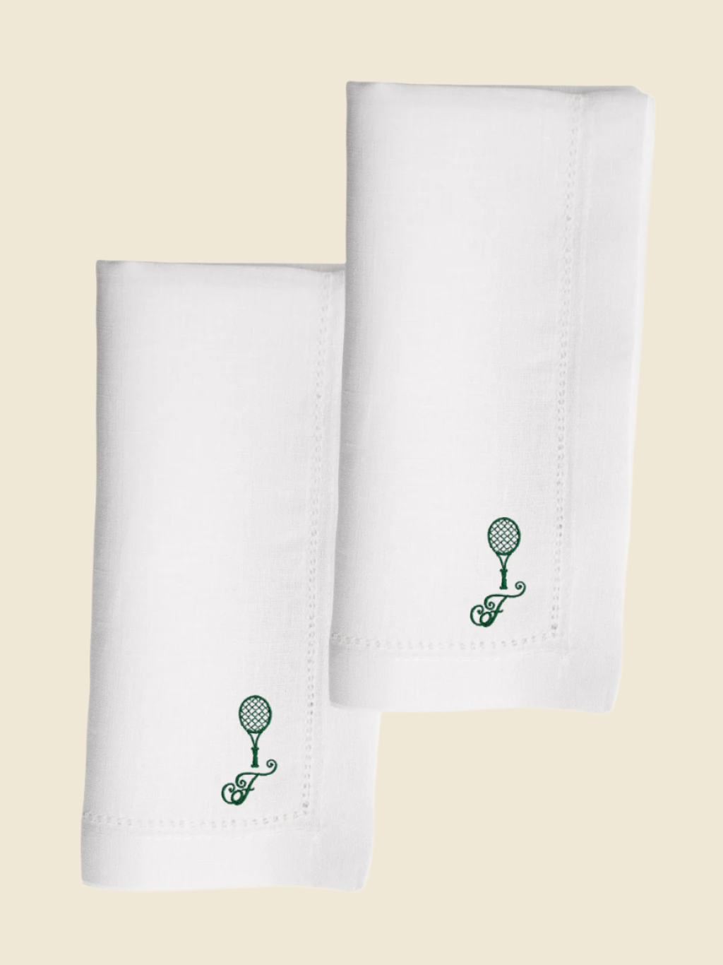 Two white napkins with green tennis racket design on a white background